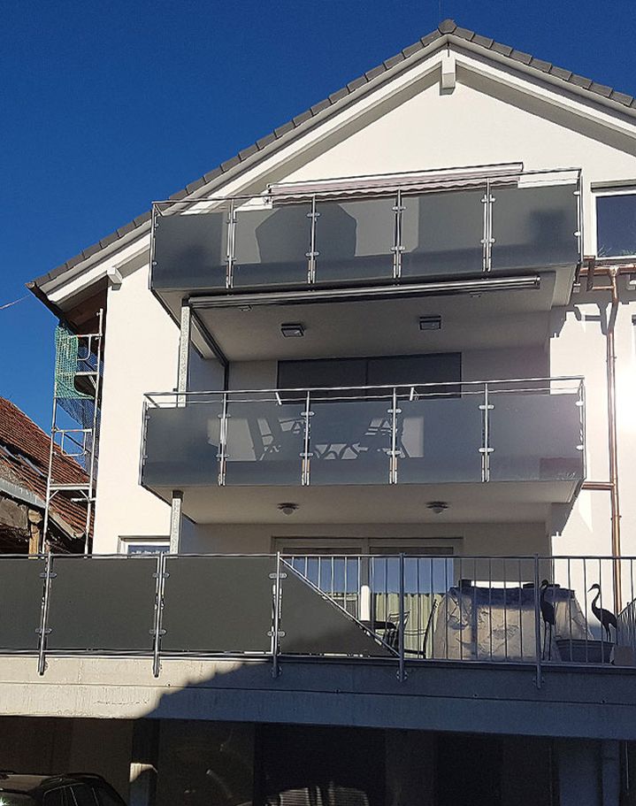 Moderne Balkon- und Terrassen-Geländer aus Edelstahl und satiniertem Glas an einem Mehrfamilienhaus, gefertigt von Creativ-Metallbau-Tamm.